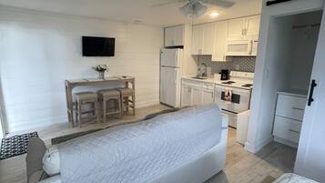 A compact living space with a kitchenette, a dining area, and a bed.