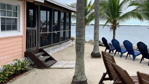 A beachfront property with a wooden building, outdoor seating, and palm trees. - Kings Kamp (Key Largo)