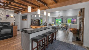 Una cocina moderna con una isla central, taburetes de bar y un comedor con vistas.