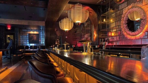 A bar area with leather seating, a long counter, and decorative lighting fixtures.