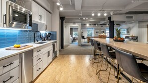 A modern kitchen with stainless steel appliances, a long counter, and a bar area with stools.