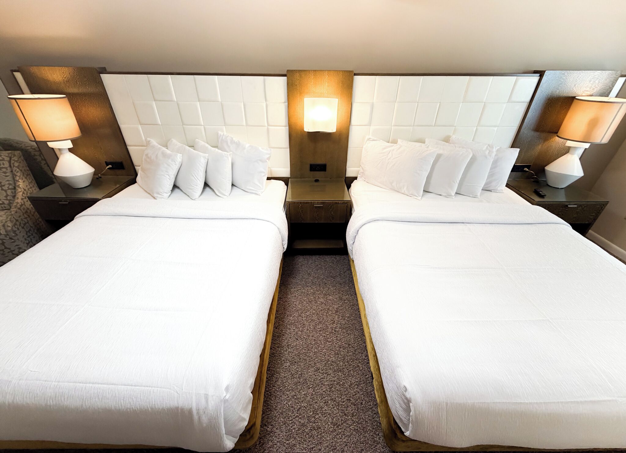 A double room with two beds, a central wall-mounted light, and bedside lamps.
