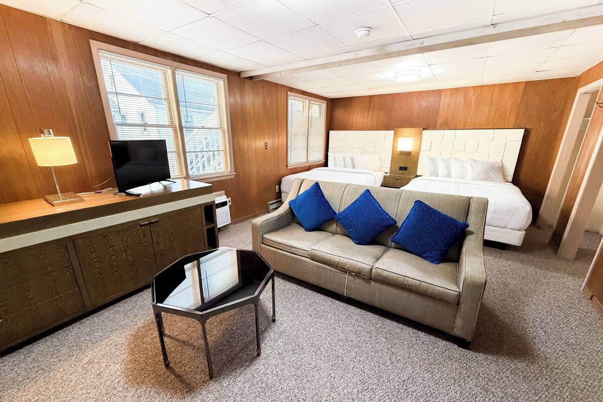 Una habitación de hotel con cama, sofá, escritorio y televisión.