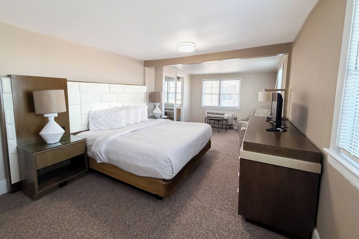 Una habitación de hotel con una cama, mesitas de noche, un escritorio y una silla.