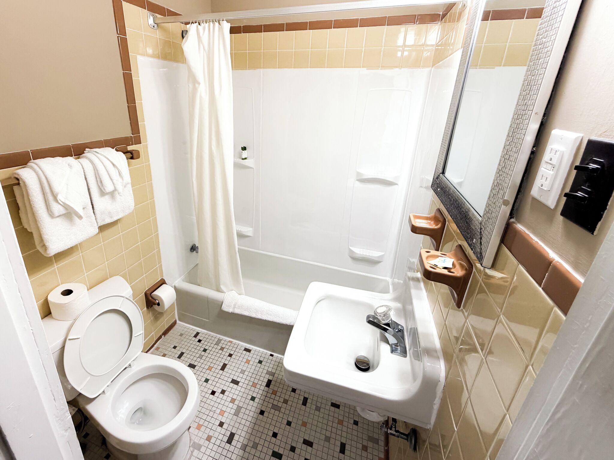 Ein Badezimmer mit Toilette, Waschbecken, Dusche und Spiegel.