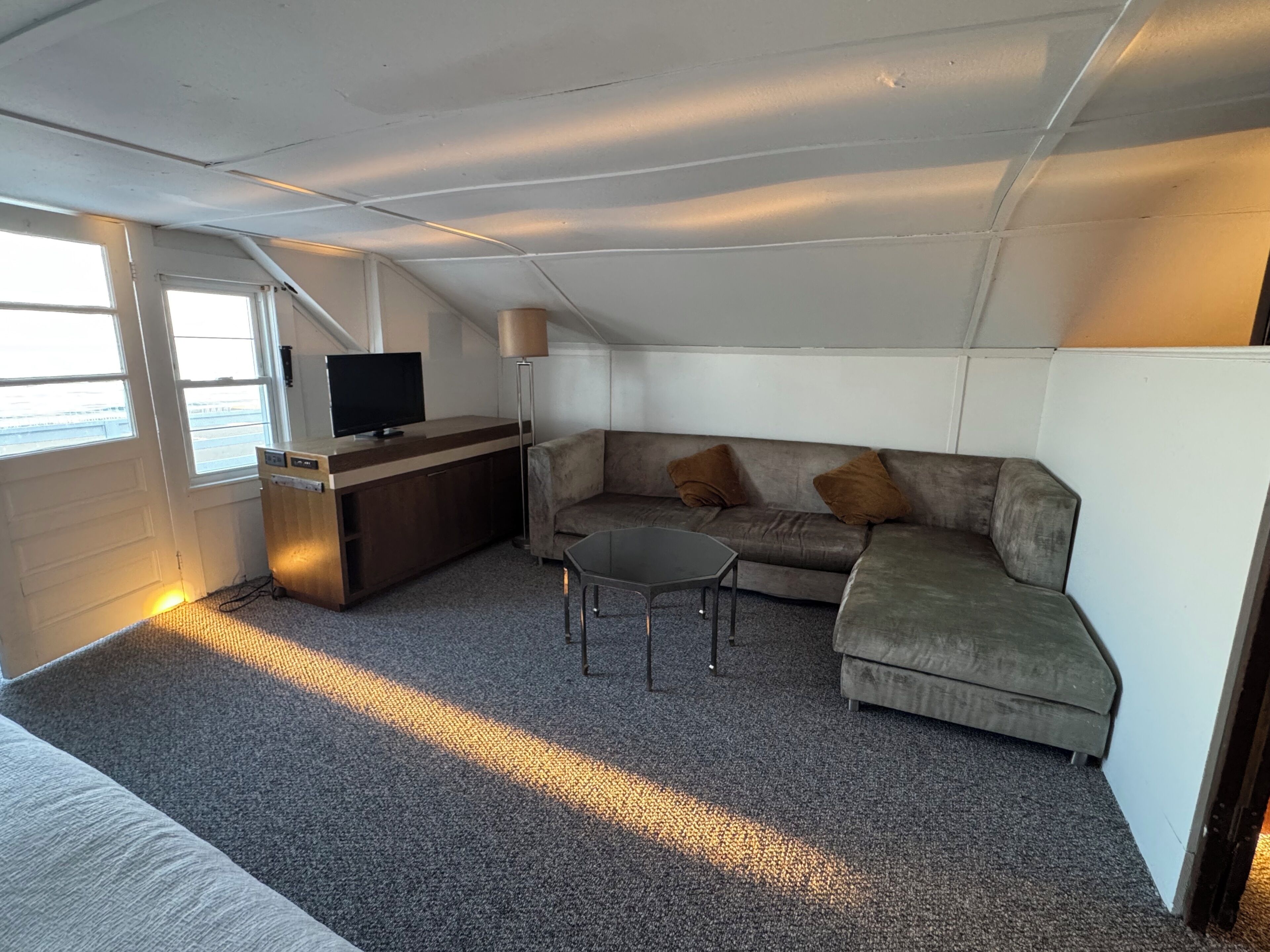 Un espacio habitable compacto con sofá, una mesita, televisor y lámpara.
