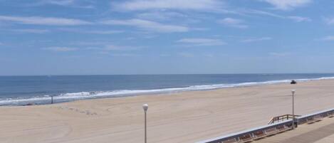 A beach with a wooden walkway and benches, overlooking the ocean.
