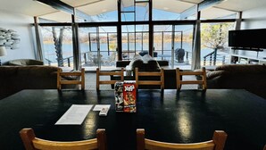 Un comedor con una mesa grande, sillas y vistas a un lago a través de amplios ventanales.