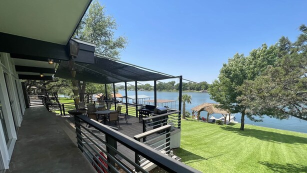 Un espacio al aire libre techado con una parrilla y asientos, con vista a un lago.