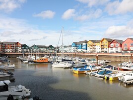 A marina with various boats docked, surrounded by colorful buildings.