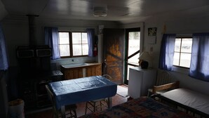 A small, dimly lit room with a bed, a table, and a kitchenette.