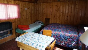 A cabin with wooden walls, a bunk bed, a single bed, a table, and a television.