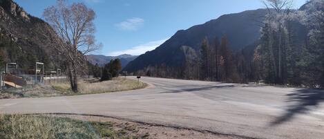 A road curving through a mountainous area with sparse trees and a clear sky.