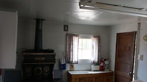 A compact kitchen with a stove, a refrigerator, a sink, and a window with curtains.