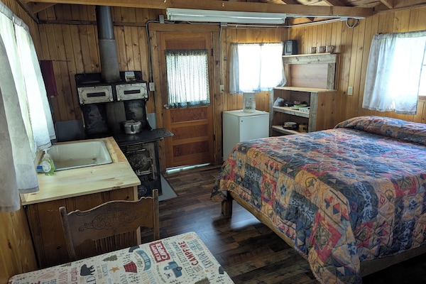 Cabin 10 is a cozy rustic cabin that features a wood-burning stove.