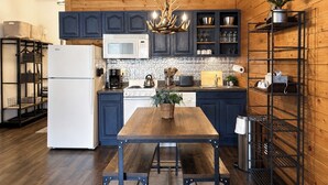 A kitchen with wooden paneling, a white refrigerator, a stove, a microwave, and a chandelier. - Walkout Studio Near W RMNP + Pool & Hot Tubs (Granby)