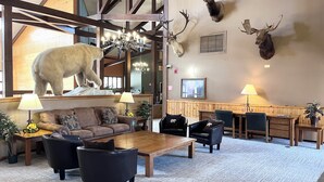 A lobby with a large wooden ceiling, a chandelier, a sofa, armchairs, a coffee table, and mounted animal heads on the wall. - Walkout Studio Near W RMNP + Pool & Hot Tubs (Granby)