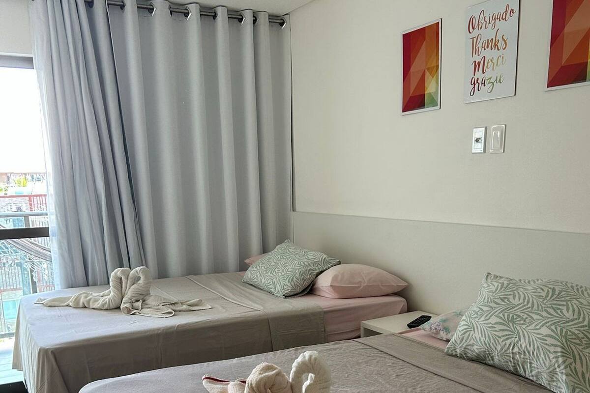 Ein Hotelzimmer mit zwei Betten, einem großen Fenster mit Vorhängen, Balkonblick und einer Wand mit mehrsprachigen Dankesschildern.