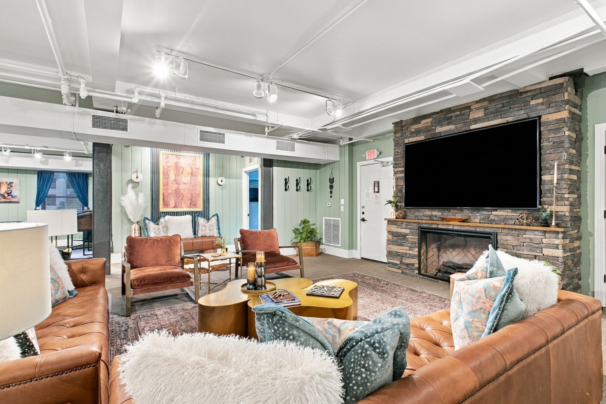 A spacious living room with a fireplace, leather sofas, and a flat-screen TV mounted on a stone wall.