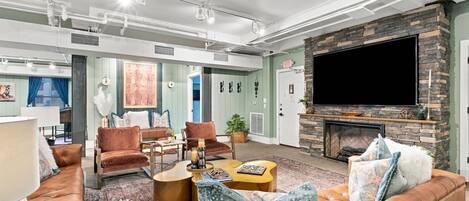 A spacious living room with a fireplace, leather sofas, and a flat-screen TV mounted on a stone wall.