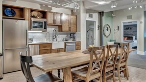 Una cocina moderna con armarios de madera, electrodomésticos de acero inoxidable y un comedor con mesa y sillas de madera.