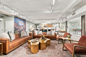 A spacious living area with a large sofa, coffee table, and chairs, a kitchen in the background, and a mural on the wall. - Music City Suite 3500sq ft Walkable to Broadway (Nashville)