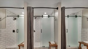 Un baño moderno con ducha envuelta en vidrio, bancos de madera y un perchero para toallas.