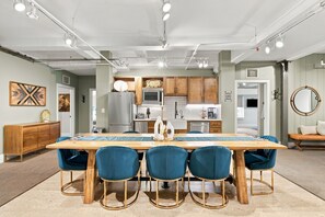 Una cocina moderna con una isla central, armarios de madera y una zona de comedor con sillas azules.