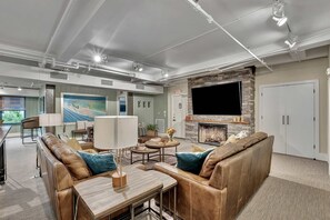 A modern living room with a fireplace, leather sofas, a flat-screen TV, and a dining area.