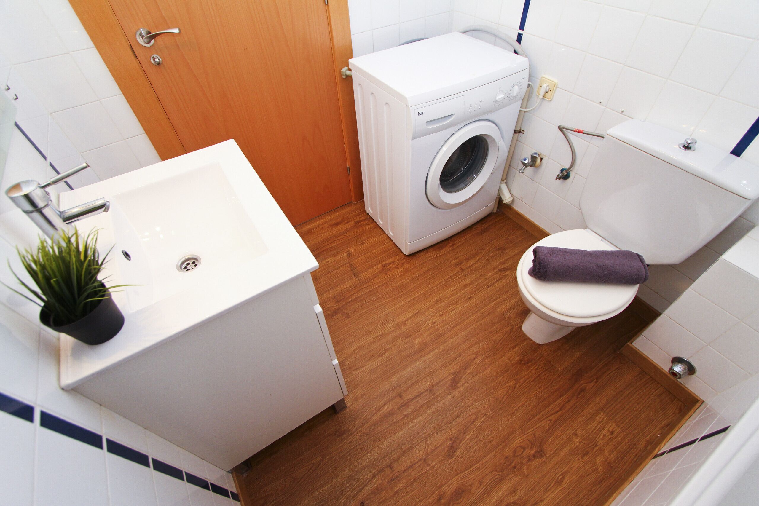 Un baño pequeño con lavadora, inodoro y lavamanos.