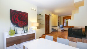 Ein modernes Wohnzimmer mit Essbereich, einem großen Gemälde einer roten Rose und einer Treppe zu einer weiteren Ebene.