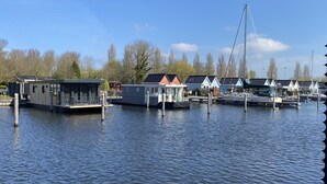 A marina with floating houses, a bridge, and calm water.