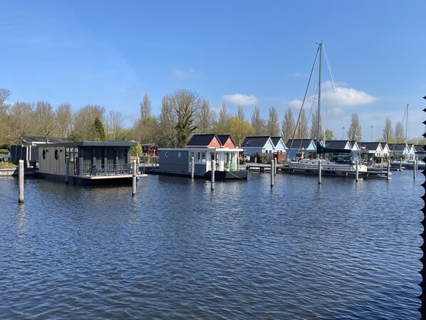 A marina with floating houses, a bridge, and calm water. - Luxury Houseboat with swim platform in colorful harbor (Stavoren)