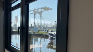 A view through a window of a bridge, a body of water, and a boat.
