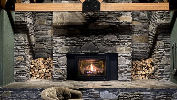 A stone fireplace with a fire, surrounded by logs. - Top 5 Pct Hotel Room with King Bed and Stunning Loon Mountain Views (Lincoln)