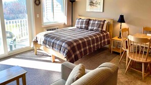 Une chambre à coucher avec un lit, un bureau, une chaise et une vue sur l’extérieur.