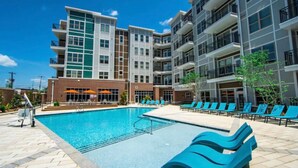 A modern building with a swimming pool, multiple balconies, and outdoor seating areas.