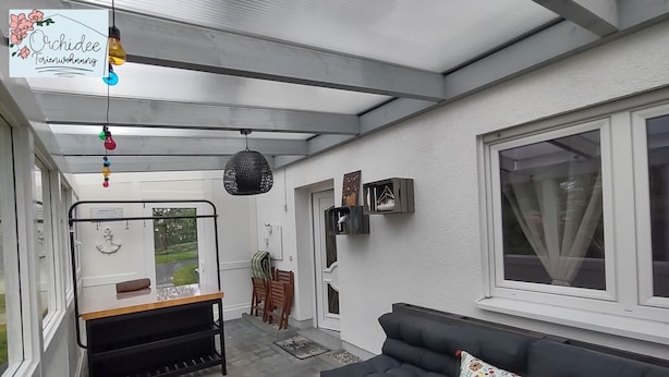 A cozy living area with a sofa, a wooden table, and a bench. There is a window with curtains, a hanging light fixture, and a wall-mounted shelf. - Quietly located vacation apartment in Reichshof Eckenhagen (Reichshof)