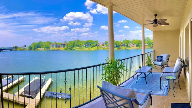 A balcony with a view of a lake, outdoor furniture, and a ceiling fan. - Stylish New Lake Condo with180° Lakefront View- Main Channel, Central Location! (Hot Springs)