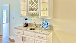 A kitchen with white cabinets, a granite countertop, a sink, a red toaster, and a decorative blue coral piece. - Stylish New Lake Condo with180° Lakefront View- Main Channel, Central Location! (Hot Springs)