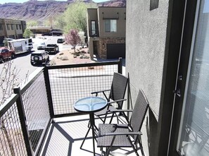 Enjoy a balcony with a table and chairs, offering a view of the surrounding mountains and parking area.