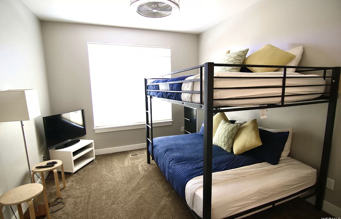 A bunk bed room with a TV and a small table.