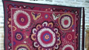 A red patterned tapestry hanging on a white brick wall. - Single Room with Private Bathroom (Buxoro)