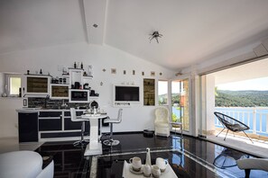 Eine moderne Küche mit Essbereich, ein großes Fenster mit Meerblick und ein Balkon mit einem Stuhl.