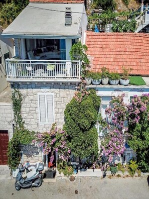 Ein zweistöckiges Gebäude mit Balkon, Steinverkleidung und Blumentöpfen.
