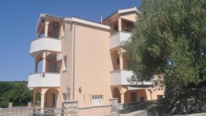 Un immeuble à plusieurs étages doté de balcons, d’un mur en pierre et d’un arbre.