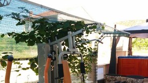 Une salle de sport en plein air équipée de matériel d’exercice, avec un espace détente et un patio couvert.