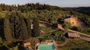Eine Vogelperspektive auf ein Anwesen mit Swimmingpool, einer Holzterrasse und einem Gebäude, das von dichtem Wald umgeben ist.