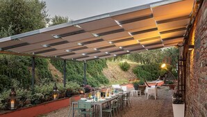 Eine Außenpatio mit überdachtem Sitzbereich, Tischen und Stühlen.