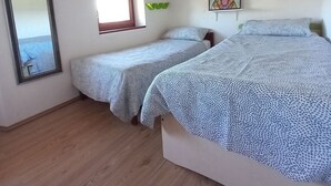 Un dormitorio con dos camas, vigas de madera en el techo, una ventana, un espejo y una obra de arte colgada en la pared.